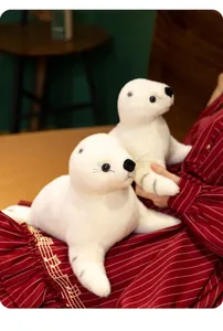 Détail de deux peluches de phoque blanches tachetées de gris tenues par un mannequin