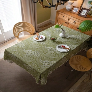 Detail of green cotton linen tablecloth with white leaf prints and fringe tassels