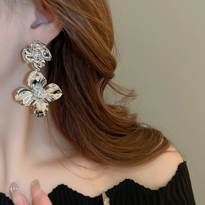 Silver flower pendant earrings shown on model with irregular metallic petal texture