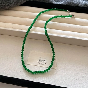 Gros plan de perles en verre vert émeraude translucides avec un fermoir mousqueton en argent
