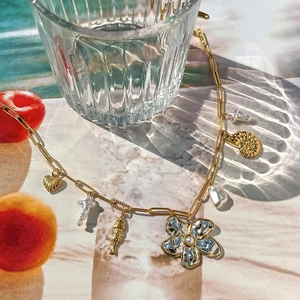 Gros plan du collier doré style océan avec breloques cœur, coquillage et perles
