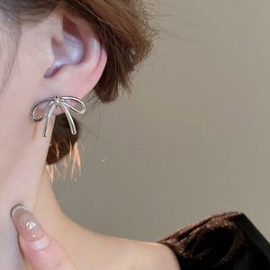 Vue détaillée d'une boucle d'oreille nœud en métal argenté aux lignes fluides et brillantes