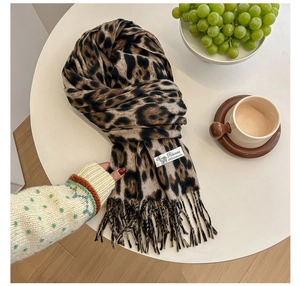 Detail shot of a cashmere scarf with leopard print, fringe, and a Pashmina label