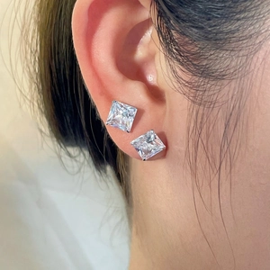Close-up of square cut zircon stud earrings on model ear showing shiny silver finish