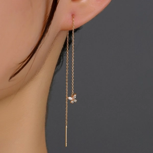 Macro shot of long gold butterfly ear threads with sparkling zircon stones on model