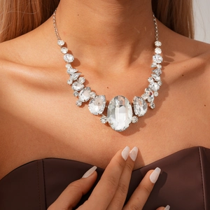 Macro detail of silver drop and oval crystal necklace set on model with luxury shine