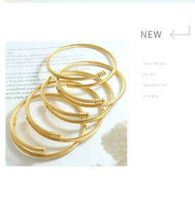 Detail of gold cable twisted cuff bracelets arranged on a decorative book page
