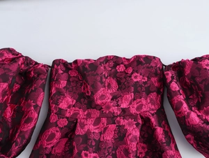 Detail of fuchsia jacquard fabric on off-shoulder dress with elegant puff sleeves