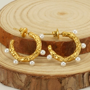 Boucles d'oreilles créoles dorées en acier titane avec perles sur support en bois