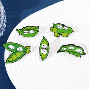 Set of creative enamel pins featuring cute white cats in green pea pods on a white plate