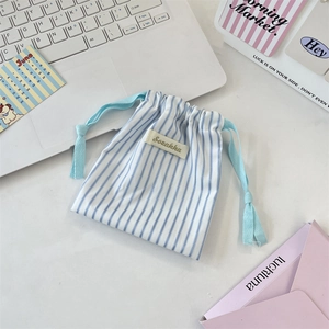 Detailed close-up of blue striped fabric storage pouch with drawstring on a desk