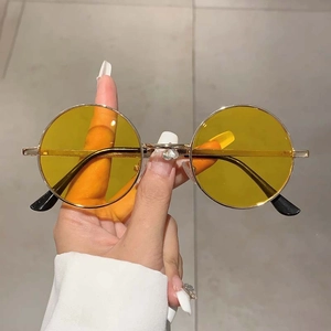 Détail de la monture ronde en métal doré et verres jaunes de lunettes de soleil vintage