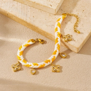 Handwoven rope chain bracelet with gold plated diamond flower charms on stone surface