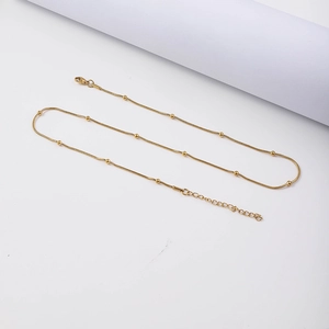 Close-up of golden stainless steel snake chain necklace with beads and lobster clasp
