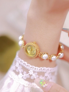 Detail of luxury gold watch with pearl bracelet strap on a female model's wrist