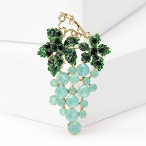 Elegant gold grape brooch with green crystals and opal stones on a white background