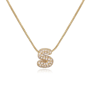 Close-up of golden necklace with crystal-embedded letter S pendant on a white background