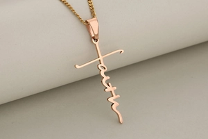 Detailed view of rose gold faith cross pendant necklace with artistic script lettering