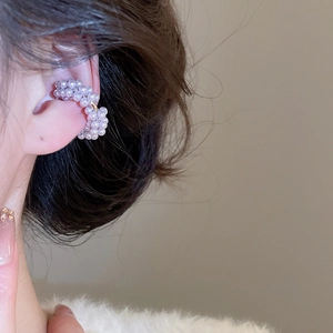 Detail of elegant pearl ear cuff featuring small white pearls in a delicate C-shape design