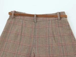 Detail of red and brown houndstooth trousers featuring a slim brown leather belt