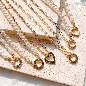 Ensemble de colliers perles baroques avec fermoir cœur et chaîne dorée sur pierre