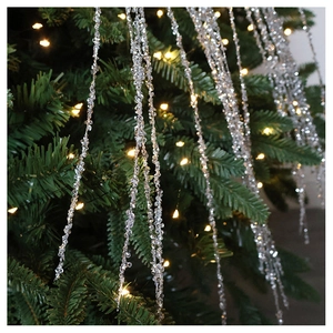 Close-up of sparkling crystal beads hanging on Christmas tree with warm festive bokeh lights