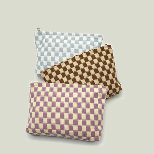 Three checkered knitted cosmetic bags in blue, brown, and purple colors with top zippers