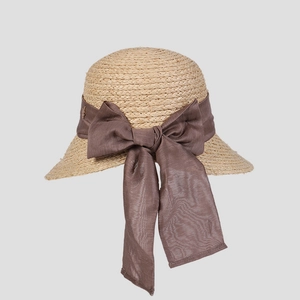 Détail du chapeau de paille montrant le tissage dense et le grand nœud en mousseline