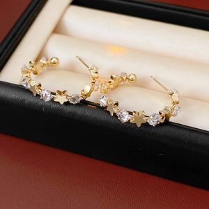 Detail of gold star hoop earrings with sparkling cubic zirconia in a jewelry box