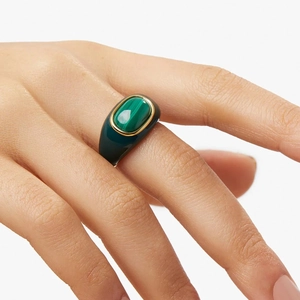 Macro view of wide dark green enamel ring featuring an oval green gemstone in gold plating