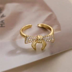 Dettaglio macro dell'anello a fiocco dorato con zirconi brillanti e design aperto