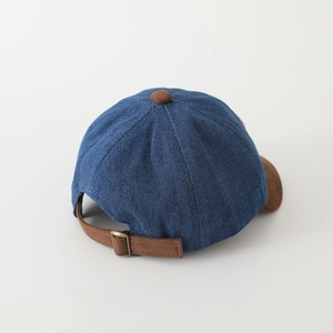 Dettaglio della fibbia in metallo e cuciture sul cappellino da baseball in denim blu