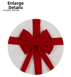 Detail showing the red velvet bow on a white plush Christmas tree skirt base