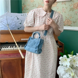 Vintage blue denim crossbody bag shown with floral dress in a retro aesthetic setting