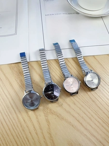 Flat lay of four minimalist chain strap quartz watches on a wooden surface with lifestyle props