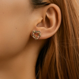 Close-up of golden heart earrings with colorful crystals worn by a female model