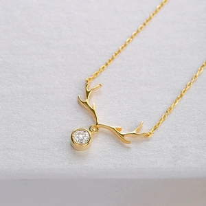 Macro shot of gold reindeer antler necklace with a sparkling round cubic zirconia pendant