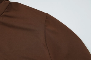 Dettaglio delle cuciture sottili e del tessuto marrone sulla spalla del vestito