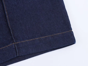 Detail aus dunkelblauem Denim mit gelben Kontrastnähten und präziser Verarbeitung