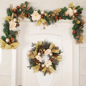 Luminous Christmas wreath set with gold ribbons and artificial flowers on a white door