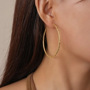 Close-up of 18k gold plated matte frosted round hoop earrings with sparkling texture