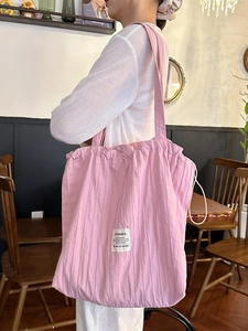 Pink pleated cotton tote bag with drawstring closure and brand label for daily commute