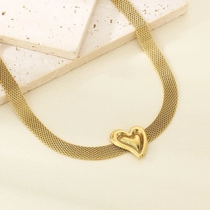 Detail of a golden mesh chain necklace featuring a layered 3D heart pendant on silk
