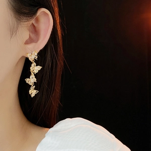 Close-up of golden butterfly tassel earrings with sparkling crystals on a model