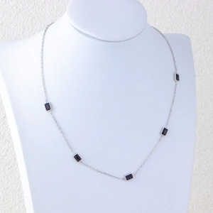 Silver thin chain necklace with five rectangular black zircon pendants on a white bust