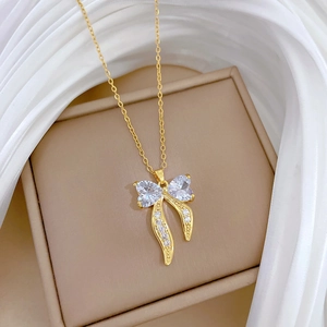 Detail shot of a golden bow pendant necklace with sparkling rhinestones on silk