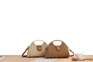 Detail of woven straw handbags in beige and brown with elegant PU leather flap and metal lock
