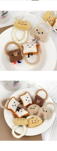Detail of plush toast-shaped hair ties with cute embroidered faces on a white plate