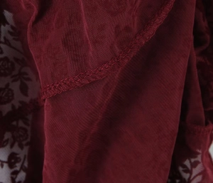 Detail of burgundy lace mesh fabric with fine floral patterns and sewing craftsmanship