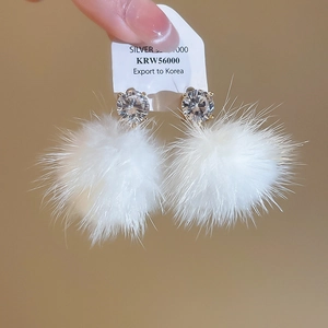 Vue détaillée de boucles d'oreilles en zircon avec pendentifs pompons en fourrure blanche